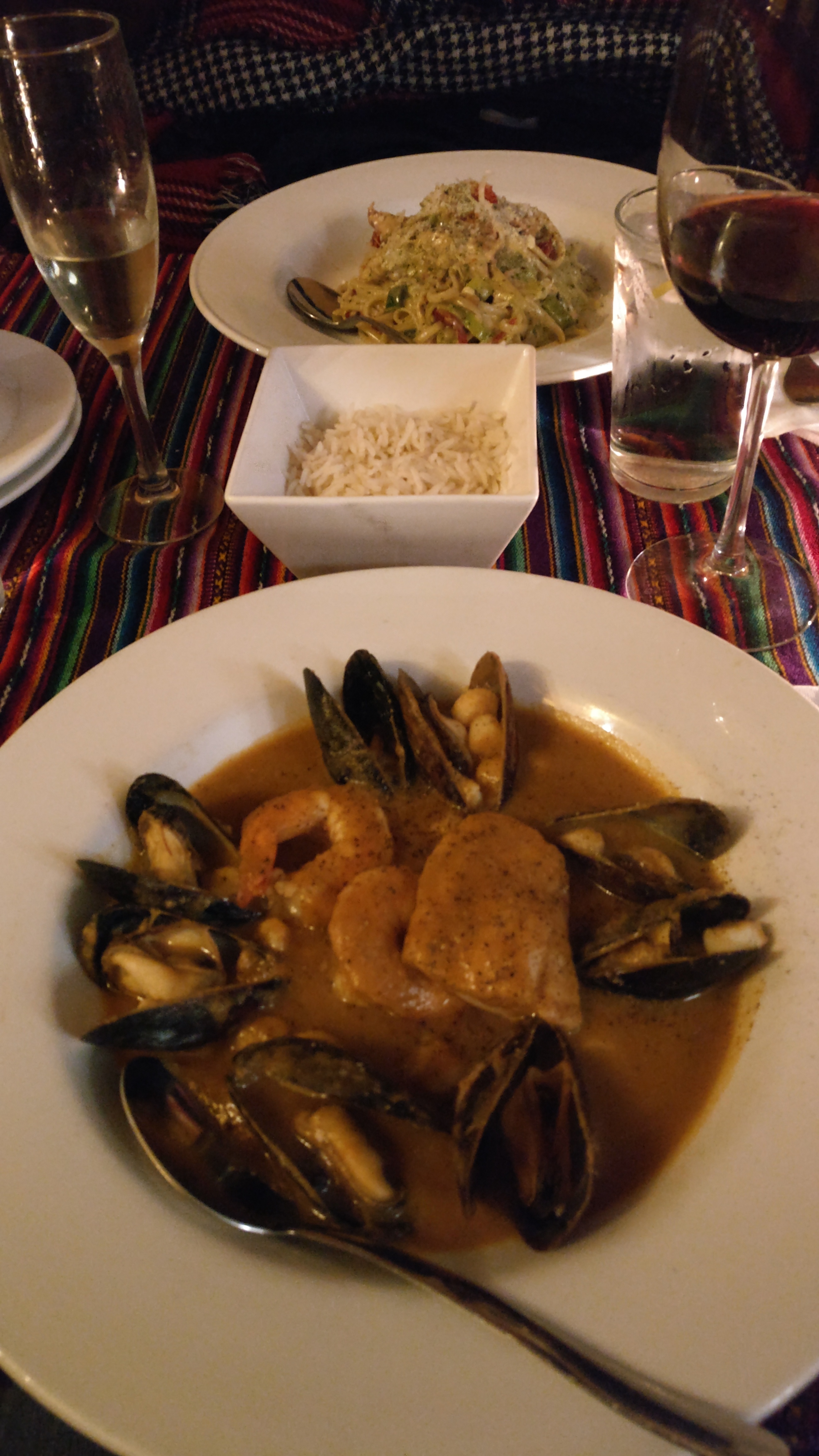 Bouillabaisse with mussels, scallops, shrimp, and fish, and a nest of pasta in the background